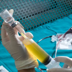 a medical professional wearing gloves injects stem cells into a vial.