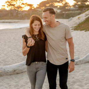 Husband and wife walking on a beach as the sun sets