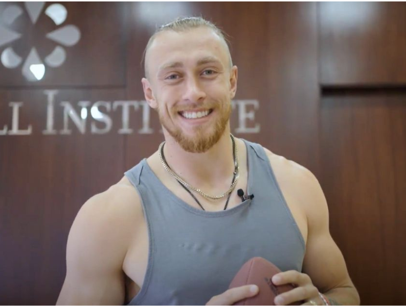 George Kittle smiling with a football at Stem Cell Institute Panama