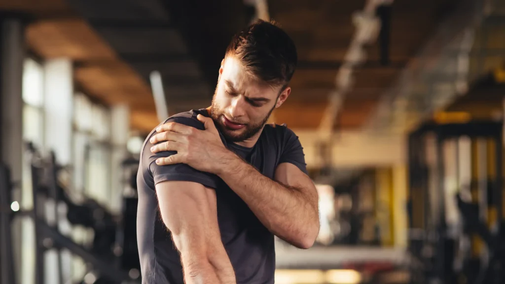 Man holding his shoulder in pain at the gym