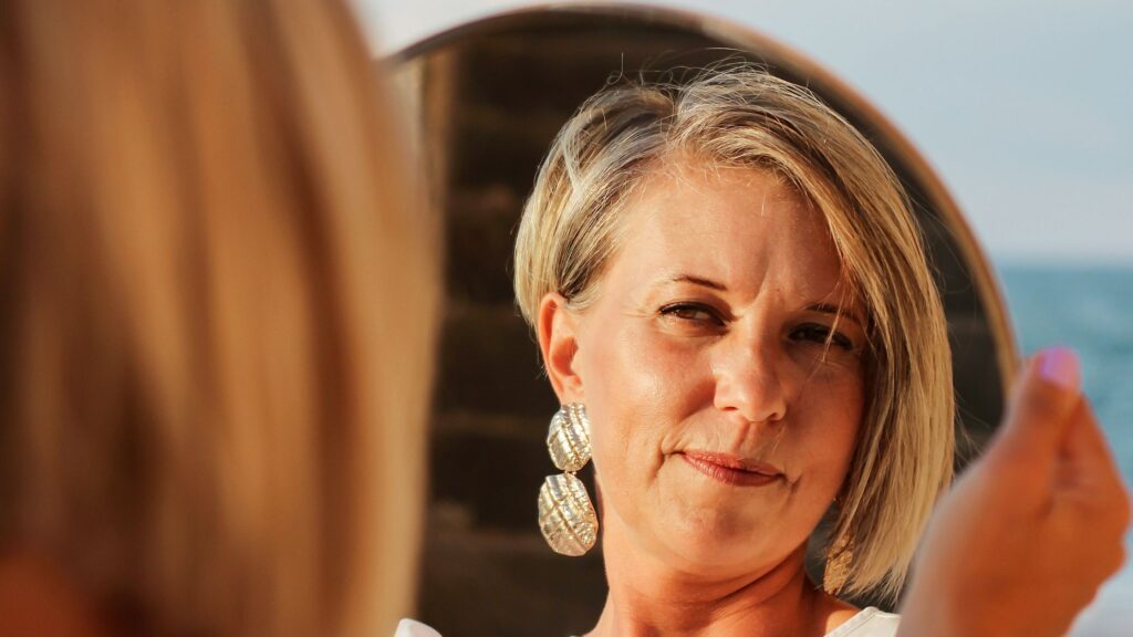 middle-aged woman examining her face in the mirror