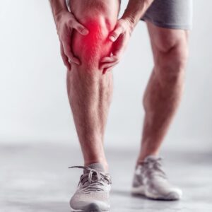 stem cell therapy for knees man in running shorts and shoes holding his knee, which is highlighted in red, in pain